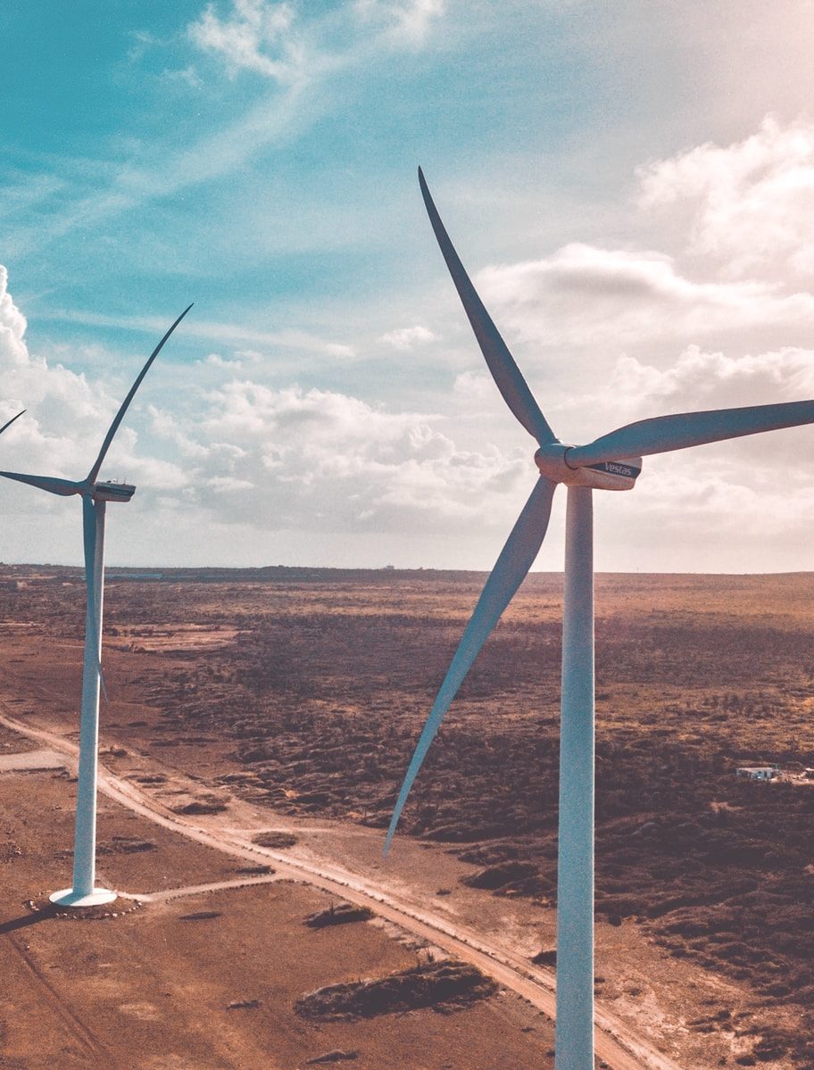 wind turbines on brown sand under white clouds and blue sky during daytime
