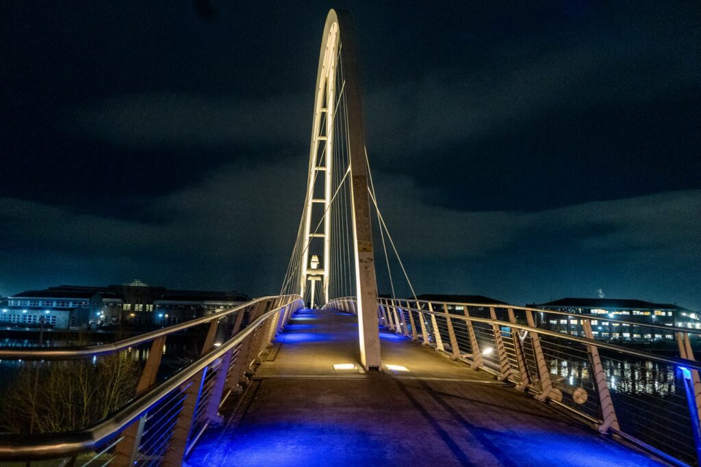 Modern illuminated bridge at night with city lights.
